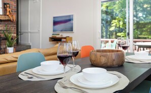 A dining table set with white plates, bowls, and wine glasses, with a wooden bowl centerpiece. - Modern A-frame cabin retreat in the woods of Middletown (Middletown)