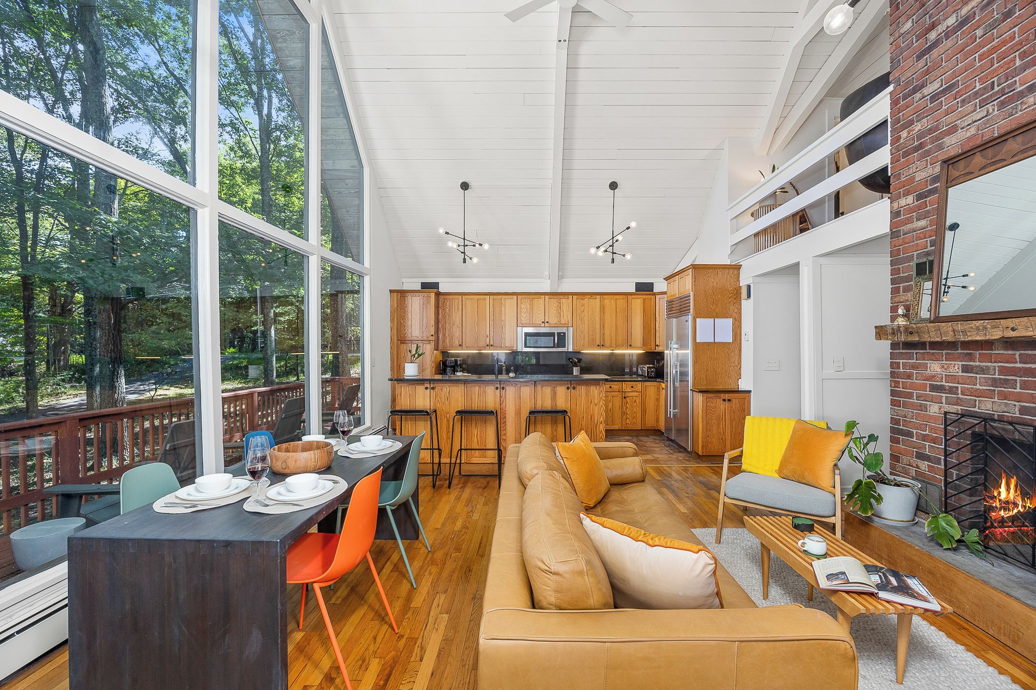 A spacious living area with a large sofa, dining table, and chairs, a kitchen with wooden cabinets, and a fireplace.