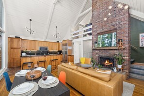 Eine moderne Küche mit Holdekor, einer zentralen Kochinsel und einem Essbereich mit Sofa und Esstisch, gedeckt für eine Mahlzeit.