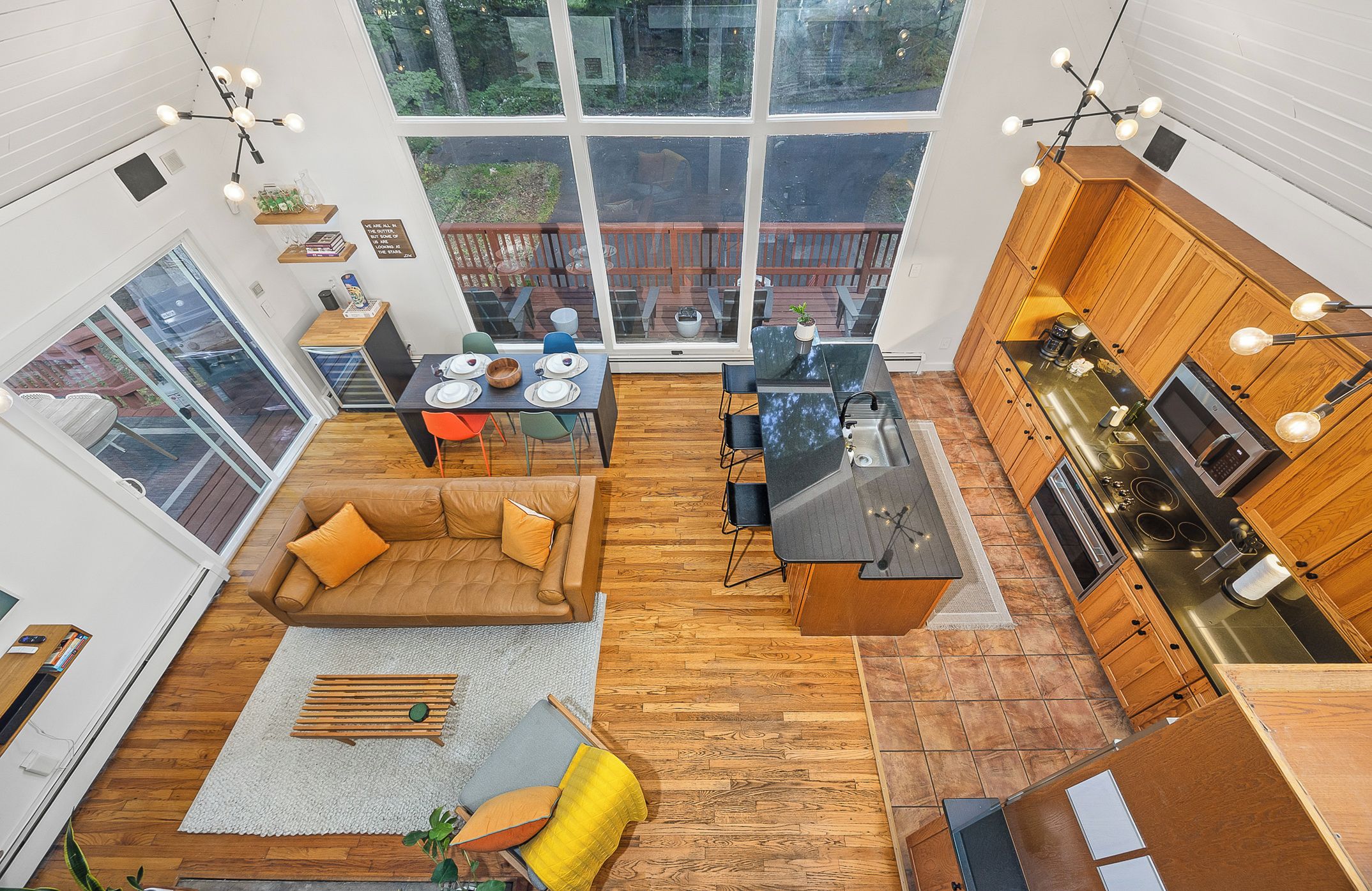 A spacious open-plan living area with a large dining table, a sofa, and a kitchen with wooden cabinets and a modern stove.