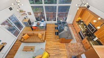 A spacious open-plan living area with a large dining table, a sofa, and a kitchen with wooden cabinets and a modern stove.