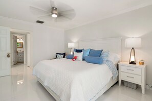 A spacious bedroom with a large bed, two bedside tables, a ceiling fan, and a nightstand with a lamp. - Charming 2-bed 2bath townhome in gorgeous Key Largo perfect monthly winter stay. (Key Largo)