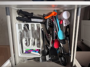 A drawer with various kitchen utensils organized in compartments.