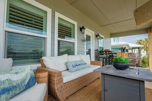 Uma área de estar coberta ao ar livre com móveis de vime, um banco e uma mesa.