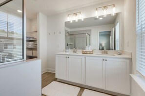 Une salle de bain moderne avec un grand meuble-lavabo, une douche à parois de verre et un grand miroir.