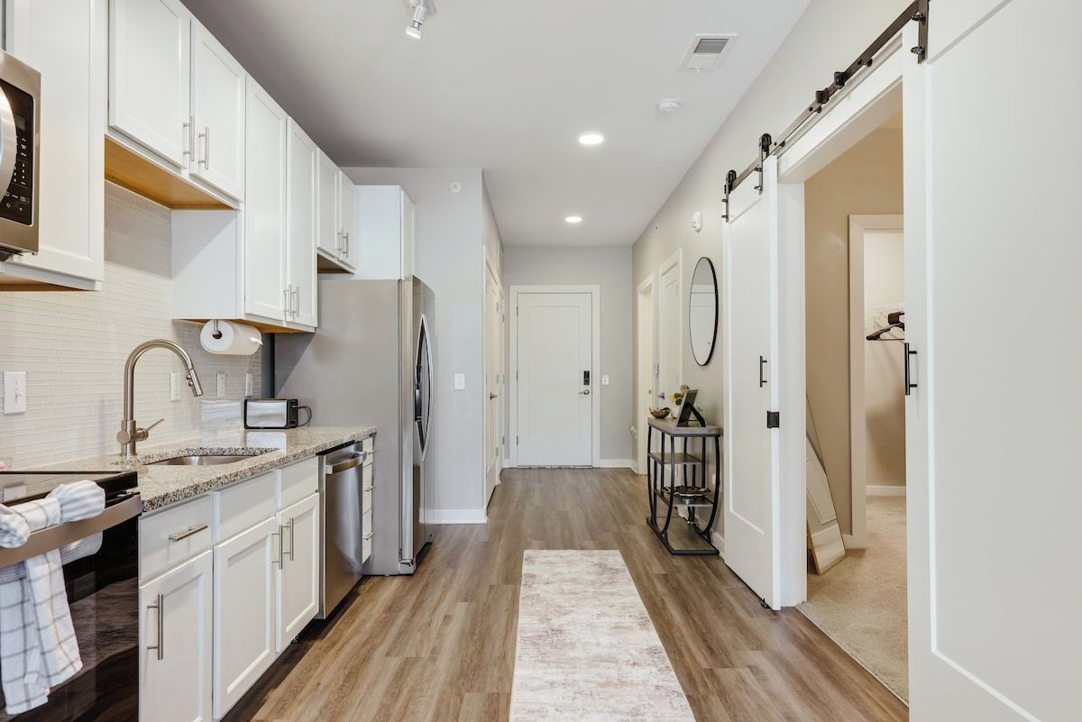 A modern kitchen with white cabinets, a stainless steel refrigerator, and a built-in oven.
