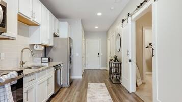 A modern kitchen with white cabinets, a stainless steel refrigerator, and a built-in oven.