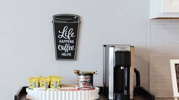 A kitchen counter with a coffee maker, a coffee cup, and a tray of coffee pods.