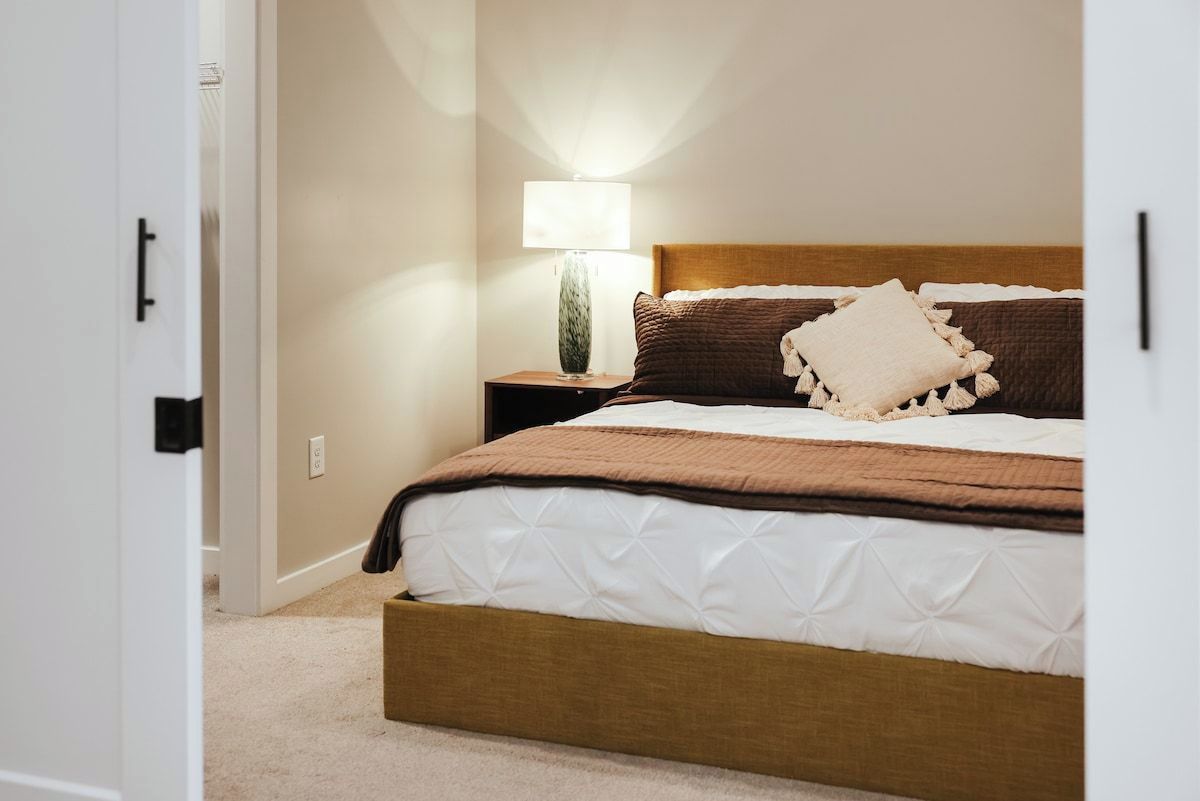 A bedroom with a bed, a nightstand, a lamp, and a door.