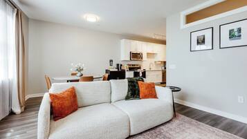 Ein modernes Wohnzimmer mit einer Couch, einem Couchtisch und einem Essbereich mit Stühlen.
