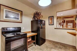 A kitchen with a stove, refrigerator, and a small countertop. - 43-Acre Cabin Retreat with Pond, Hot Tub & Windrock Park Trail Access (Oliver Springs)