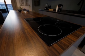 Una cocina con encimera de madera y placa de cocción por inducción negra.