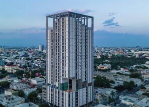 A high-rise building with a grid-like facade, surrounded by a densely populated urban area. - Iconicah (Monterrey)