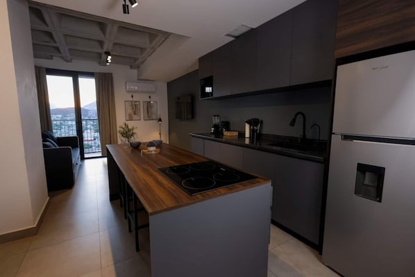Una cocina moderna con una isla central, electrodomésticos integrados y vistas al exterior.