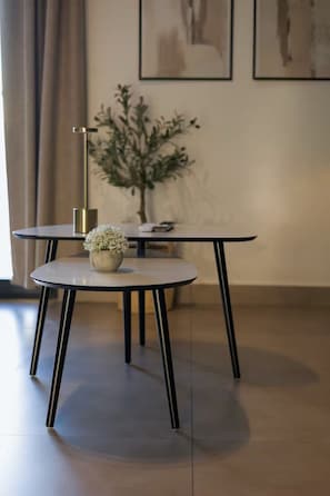 Un comedor moderno con dos mesas redondas, una con una pequeña planta encima, y una lámpara de pie alta.