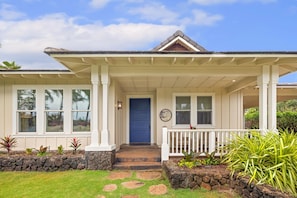 A house with a front porch, a blue door, and a stone wall. - Poipu Luxury Retreat, Sleeps 14, Walk to the beach, Pool, AC + Ohana (Koloa)