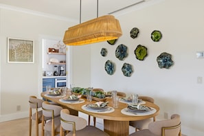 Een eetruimte met een ronde tafel, stoelen en een hanglamp.