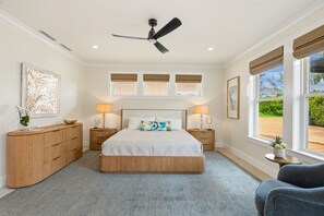 Een slaapkamer met een bed, nachtkastjes, een plafondventilator en een raam met uitzicht.