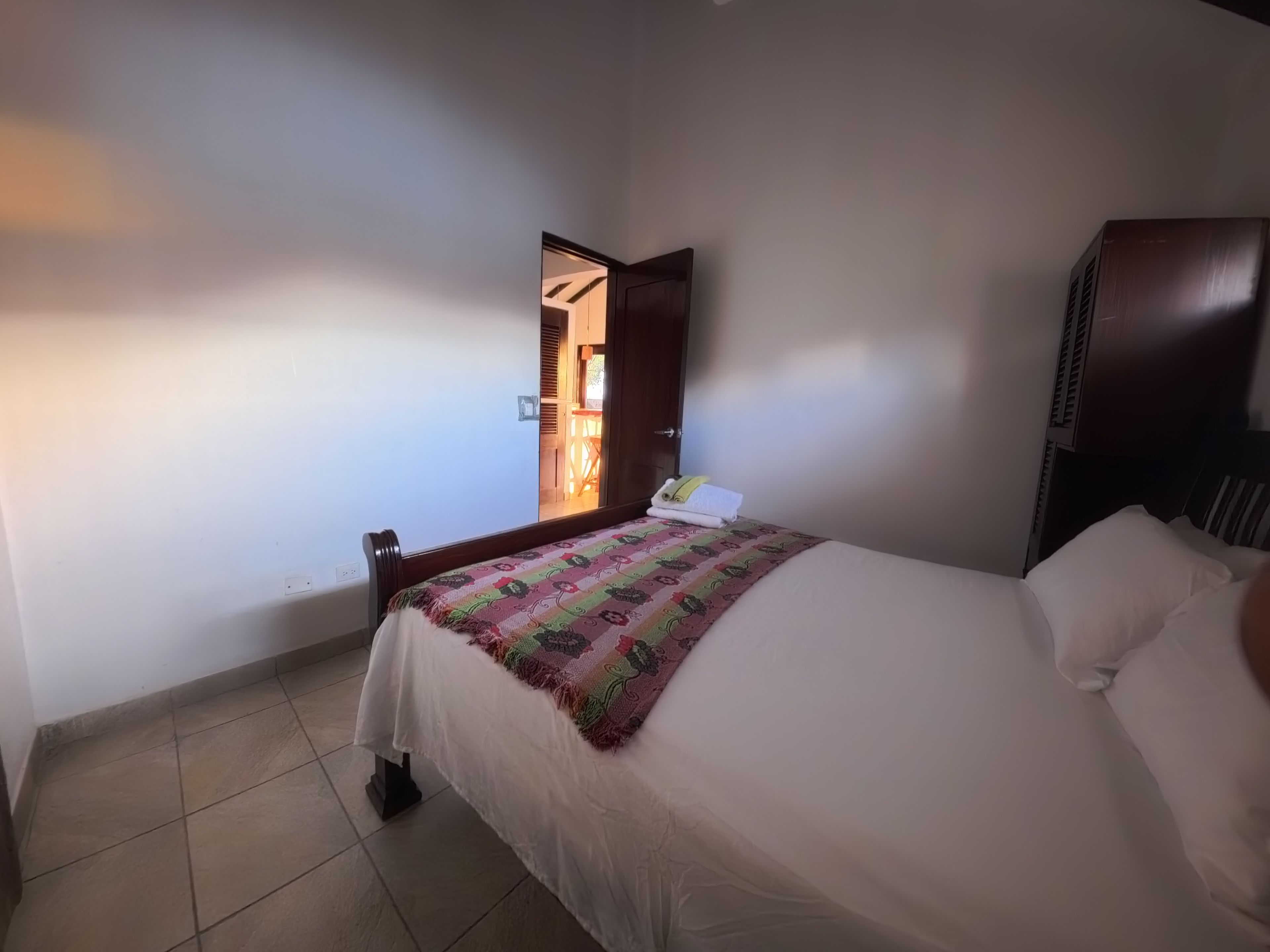 Habitación de hotel con una cama, mesita de noche, armario y vistas al exterior.