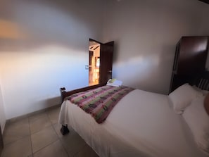 A hotel room with a bed, a nightstand, a wardrobe, and a view of the outside.
