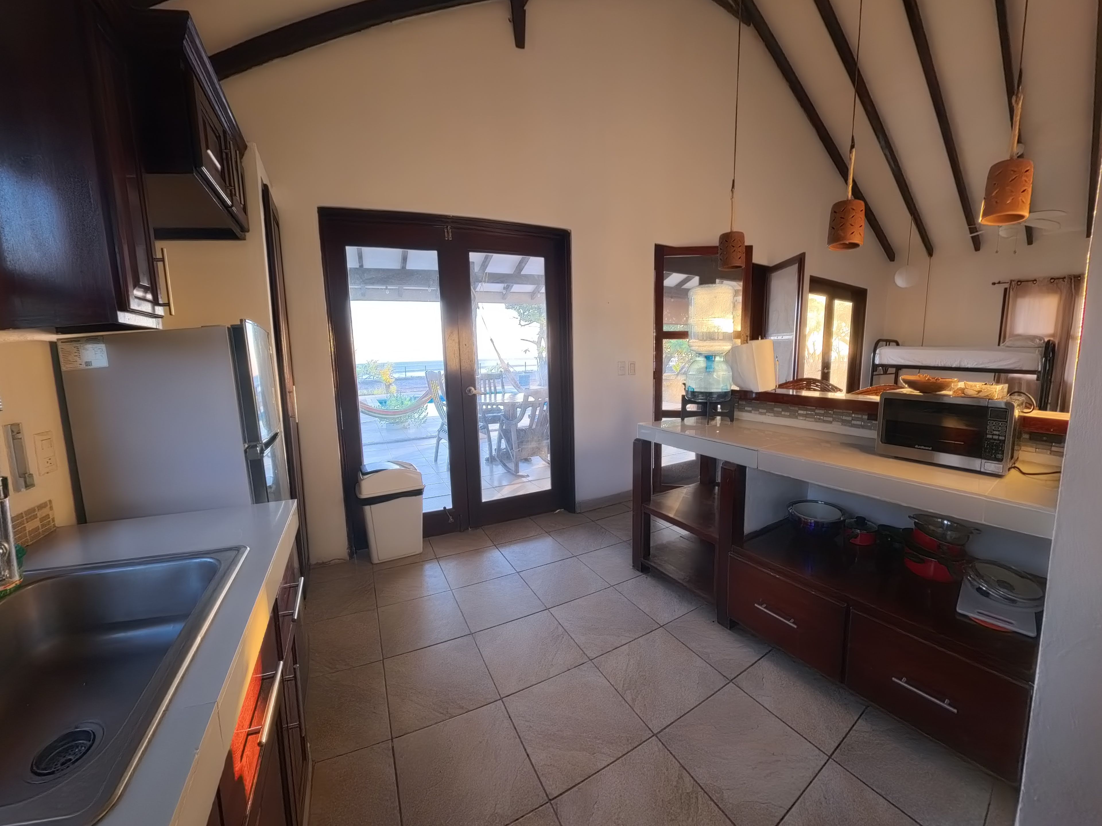 A kitchen with a refrigerator, microwave, and a view of the outdoors through a glass door.
