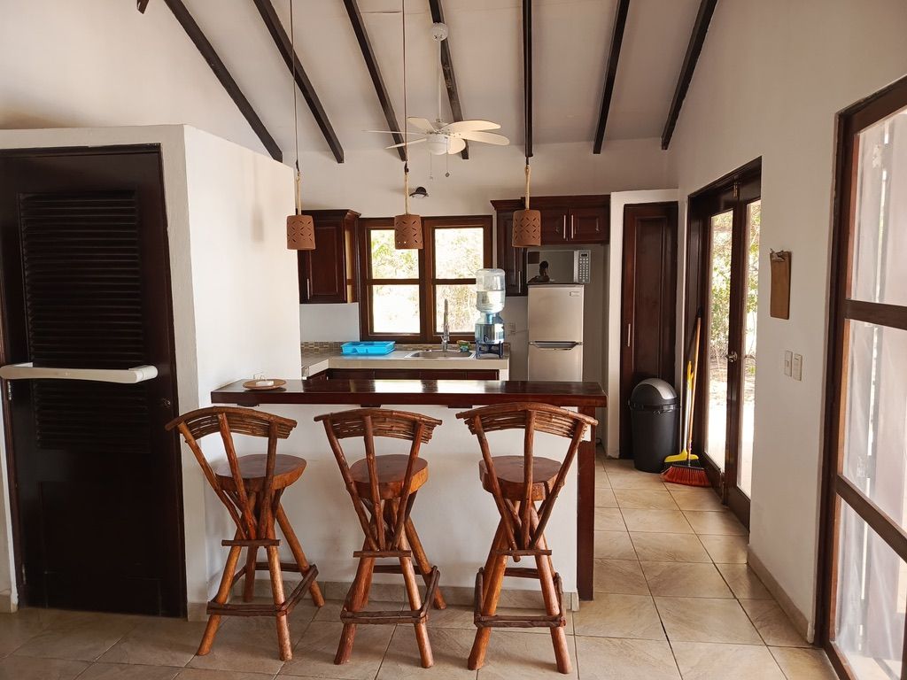 A kitchen with a central island, wooden chairs, a ceiling fan, and a view of the outdoors.