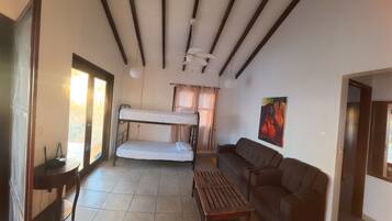 Una habitación con una cama litera, un sofá, una mesita y un ventilador de techo.