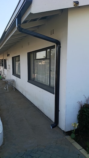 A building with a white exterior, large windows, and a visible black gutter.