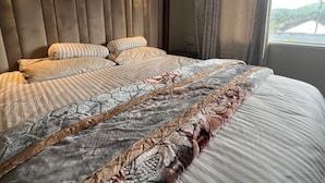 Una cama con cabecera, almohadas y una colcha estampada.