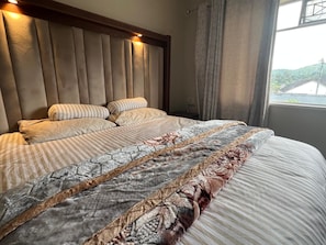 Un lit avec une tête de lit, des oreillers et une couvre-lit à motifs.