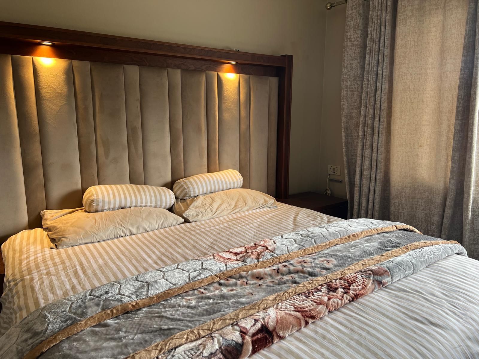 Een bed met hoofdbord, kussens en dekbed.