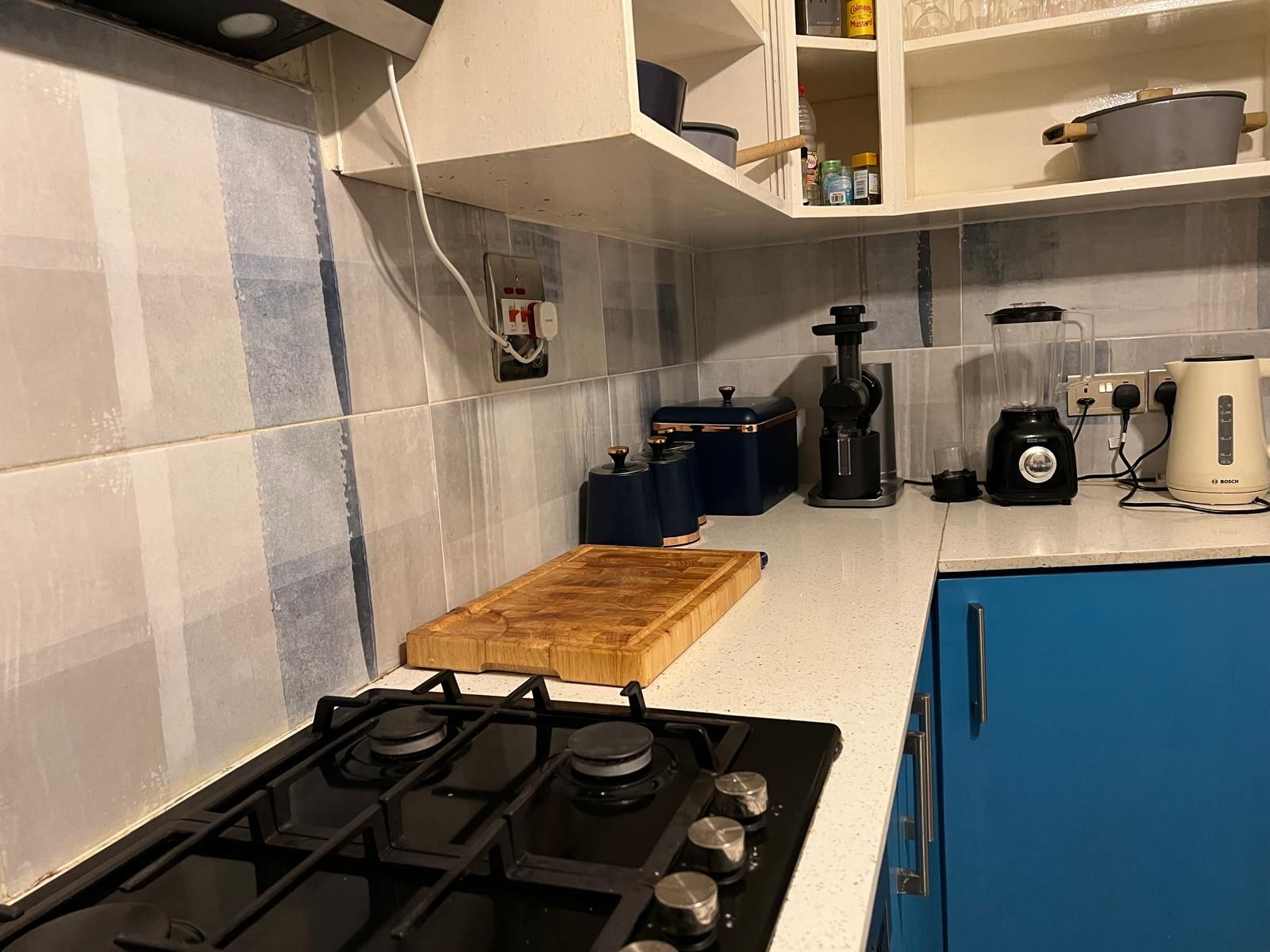 A kitchen with a gas stove, a wooden cutting board, a coffee maker, and a blender.