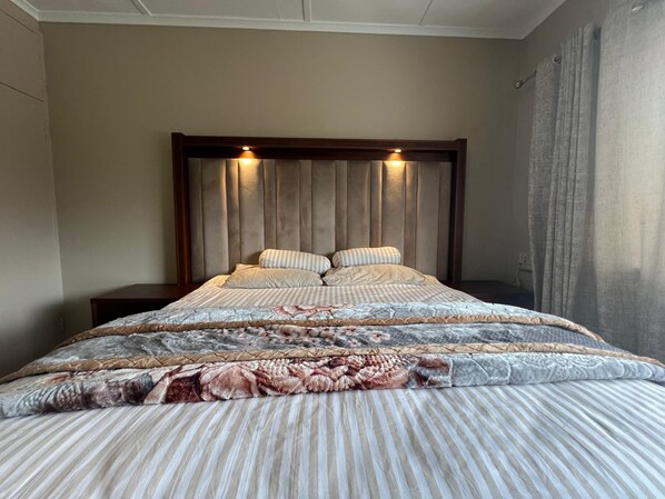 A bed with a headboard, multiple pillows, and a patterned bedspread.