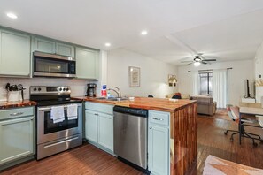 A modern kitchen with stainless steel appliances, a wooden island, and light blue cabinetry.