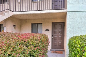 A residential building with a brown door, a window with blinds, and a small balcony with a railing. - 2BR Savannah condo w/ pool, WiFi, parking, full kitchen * 30+ days (Savannah)