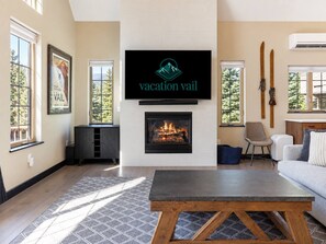A living room with a fireplace, a mounted television, and a ski rack. - Spacious Avon Townhome - Views of Beaver Creek (Avon)