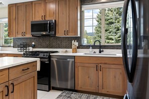 A modern kitchen with wooden cabinets, a stainless steel dishwasher, a black microwave, and a gas stove. - Spacious Avon Townhome - Views of Beaver Creek (Avon)