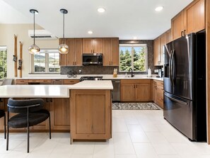A modern kitchen with wooden cabinets, stainless steel appliances, and pendant lighting. - Spacious Avon Townhome - Views of Beaver Creek (Avon)