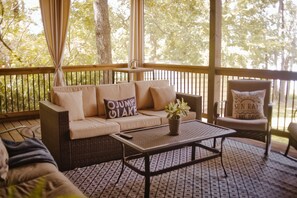 A covered outdoor seating area with a sofa, armchairs, and a coffee table. - Lakefront Retreat on Greers Ferry Lake with EV Charger (Higden)