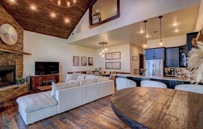 A spacious living area with a fireplace, a large sofa, and a dining table.