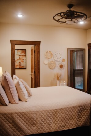 A bedroom with a bed, pillows, a ceiling fan, and wall decorations. - Lakefront Retreat on Greers Ferry Lake with EV Charger (Higden)