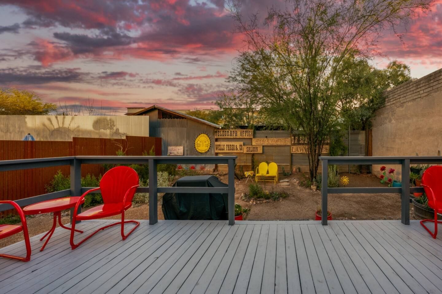 A wooden deck with red chairs, a barbecue grill, and a sign for a law office.