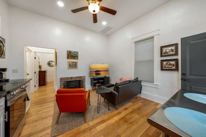 A modern living room with a fireplace, a dining area, and a kitchen with a stove. - Charming & Cozy / 1 BR 1 BA / Historic Duplex (Tucson)