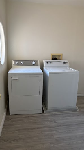 Two stacked laundry machines in a corner with a wooden floor and a plain wall. - Clean, Quiet & Cozy Housing in Summerlin, convenient to Red Rock National Park (Las Vegas)