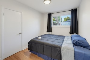 A bedroom with a bed, a window with curtains, a door, and a view of the outside.