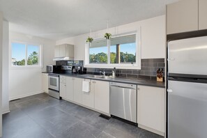 A modern kitchen with a dishwasher, oven, microwave, and a coffee maker.