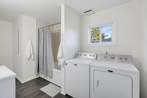 Une buanderie équipée de deux machines à laver, d’un sèche-linge, d’une fenêtre avec vue et d’un espace douche.