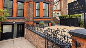 Un immeuble en briques avec un portail en métal noir et une enseigne indiquant « Manere Apartments ».