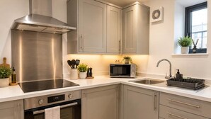 Une cuisine moderne dotée d’appareils électroménagers en acier inoxydable, de meubles de rangement gris et d’une fenêtre offrant une belle vue.