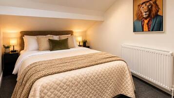 A bedroom with a bed, nightstands, a radiator, and a painting on the wall.